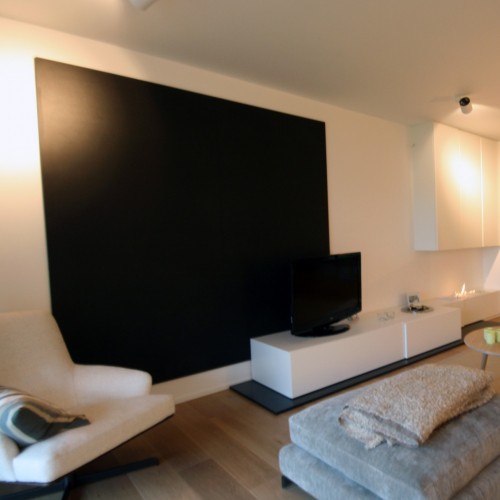 In deze woonkamer maakten we een TV-wand en een laag TV-meubel op maat, waarin plaats voorzien is voor allerlei hifi toestellen en zachte dekentjes om de zithoek gezellig te maken. Kast-ID Antw